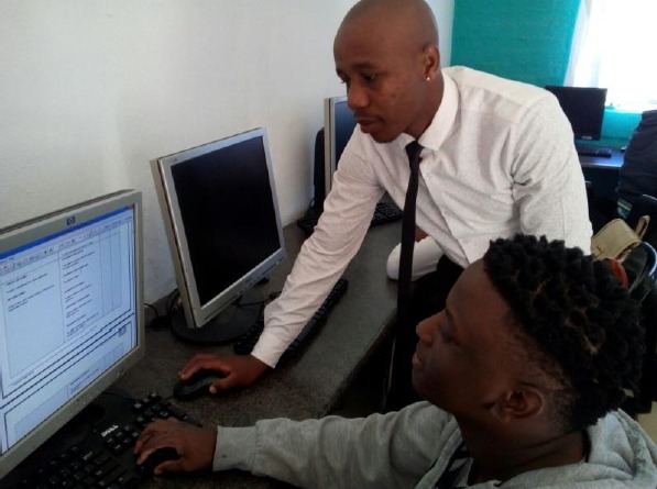 A teacher and a learner working on a computer.